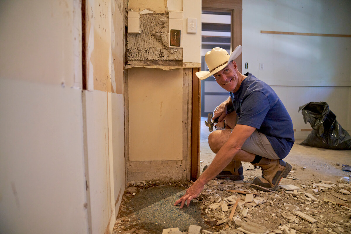 Brett Waterman crouching during a home renovation in an episode of 'Restored' on Magnolia Network