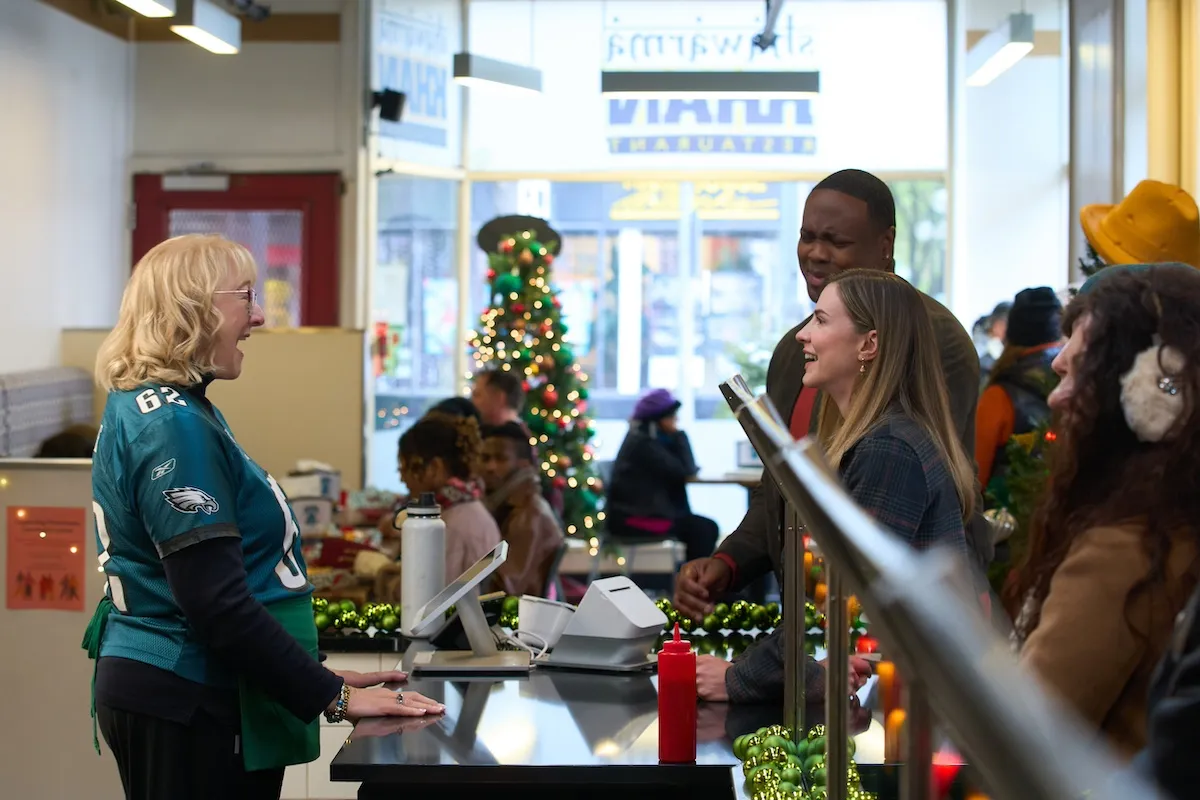 Donna Kelce standing behind the counter of a sandwich shop and talking to a man a woman in' Christmas on Call'